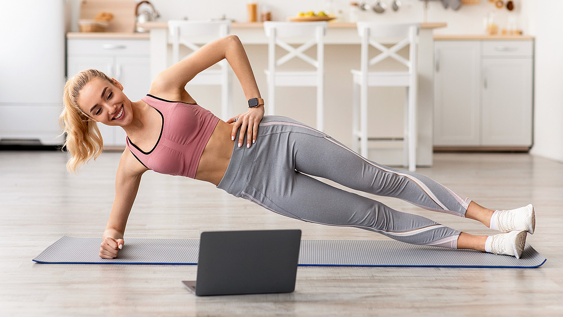 Frau macht Übungen vor einem Laptop