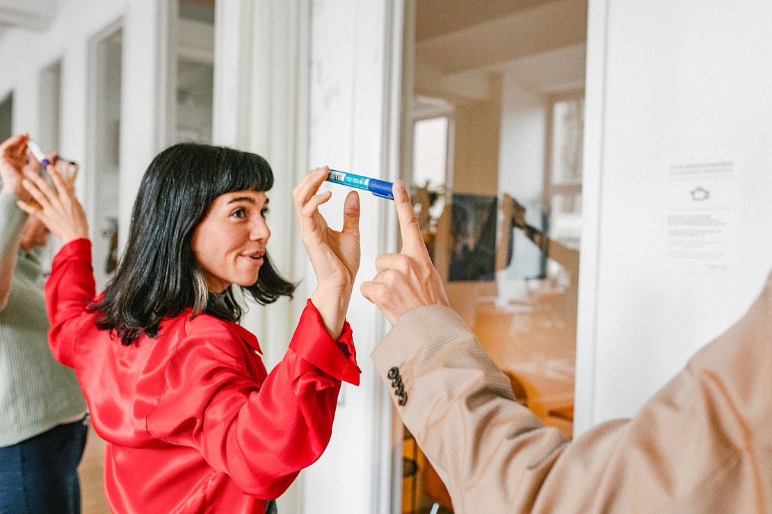 Zwei Menschen halten einen Stift zwischen den Zeigefingern