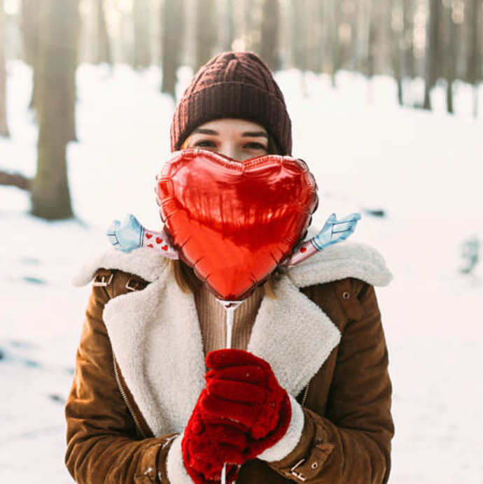 Frau hält einen Herzluftballon in der Hand