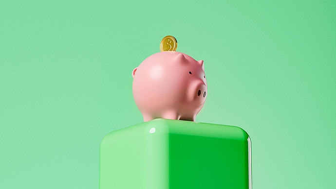 Auf einem glänzend grünen Sockel vor einem einfarbigen hellgrünen Hintergrund steht ein rosa Sparschwein mit einer eingelegten Goldmünze obendrauf.