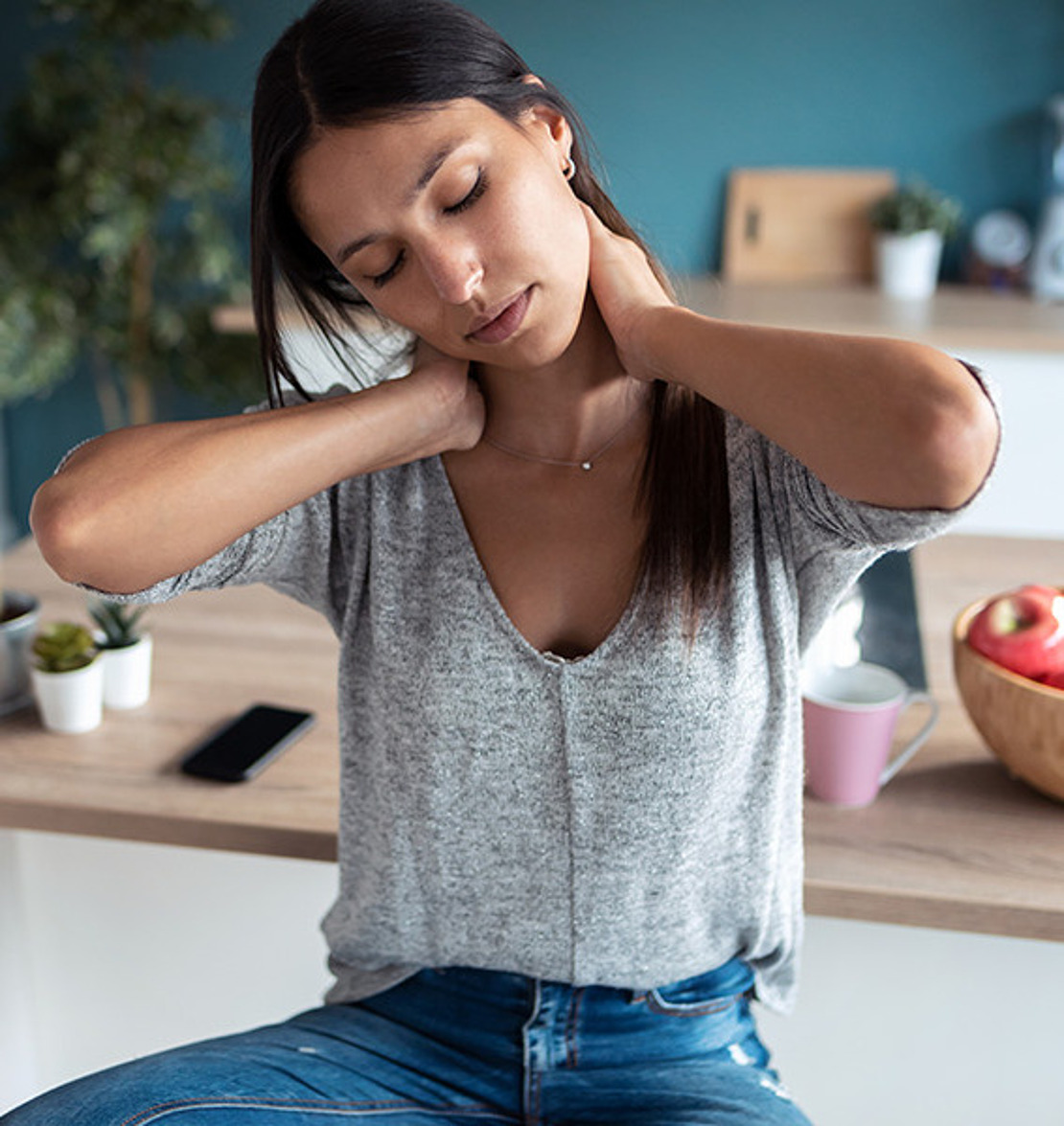 Frau legt Kopf zur Seite und legt die Hände in den Nacken