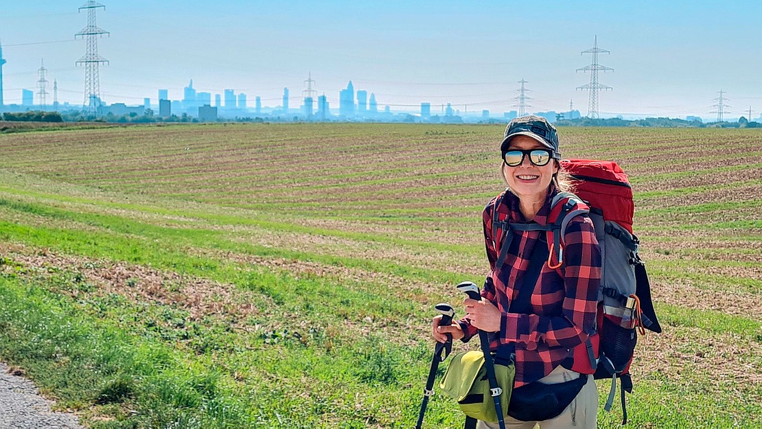 Frau, Marion Riedel, mit Wanderstöcken an einem Feld