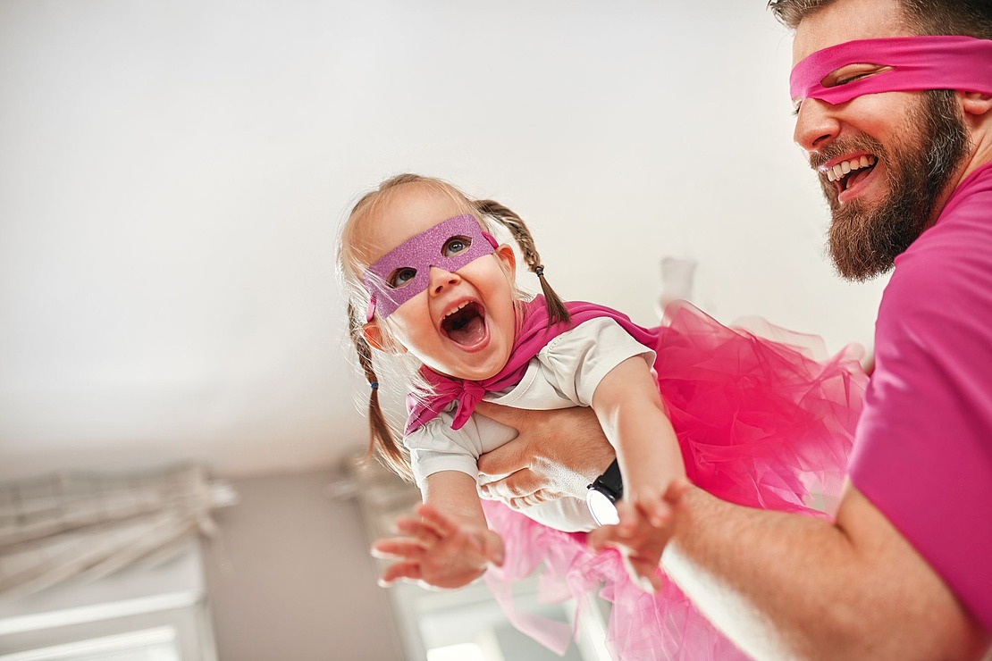 Papa spielt mit Kind Superwoman und Superman