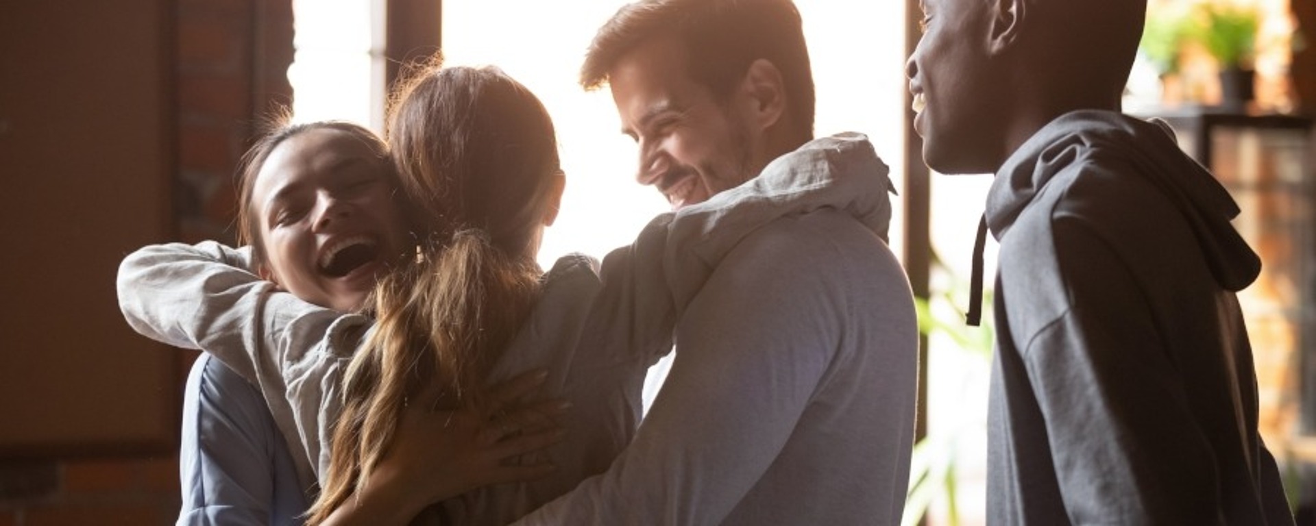 Vier Personen umarmen sich, strahlen Freude und Teamgeist aus.