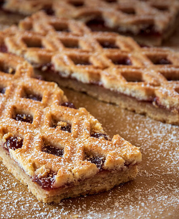 Drei rechteckige, mit Früchten gefüllte Blätterteigscheiben werden auf Pergamentpapier ausgelegt und mit Puderzucker bestäubt.