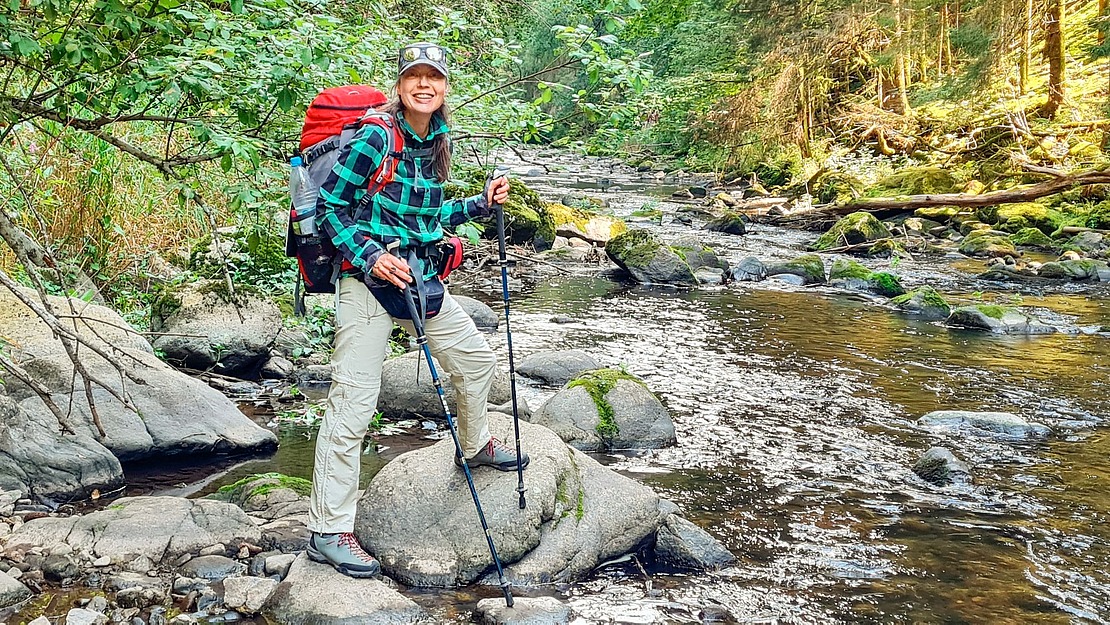Frau, Marion Riedel, steht auf Steinen an einem Bach